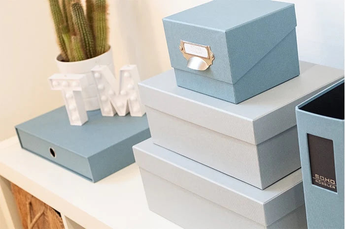 Foto Aufbewahrungsbox mit Metallgriff in der Farbe denim-blau stehend auf zwei gestapelten Aufbewahrungsboxen in hellem blau.